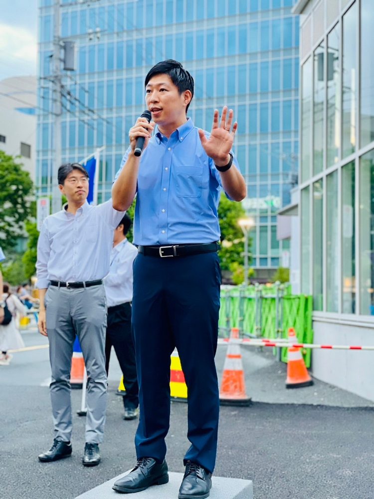 マイクを持って街頭演説するいいだ健一