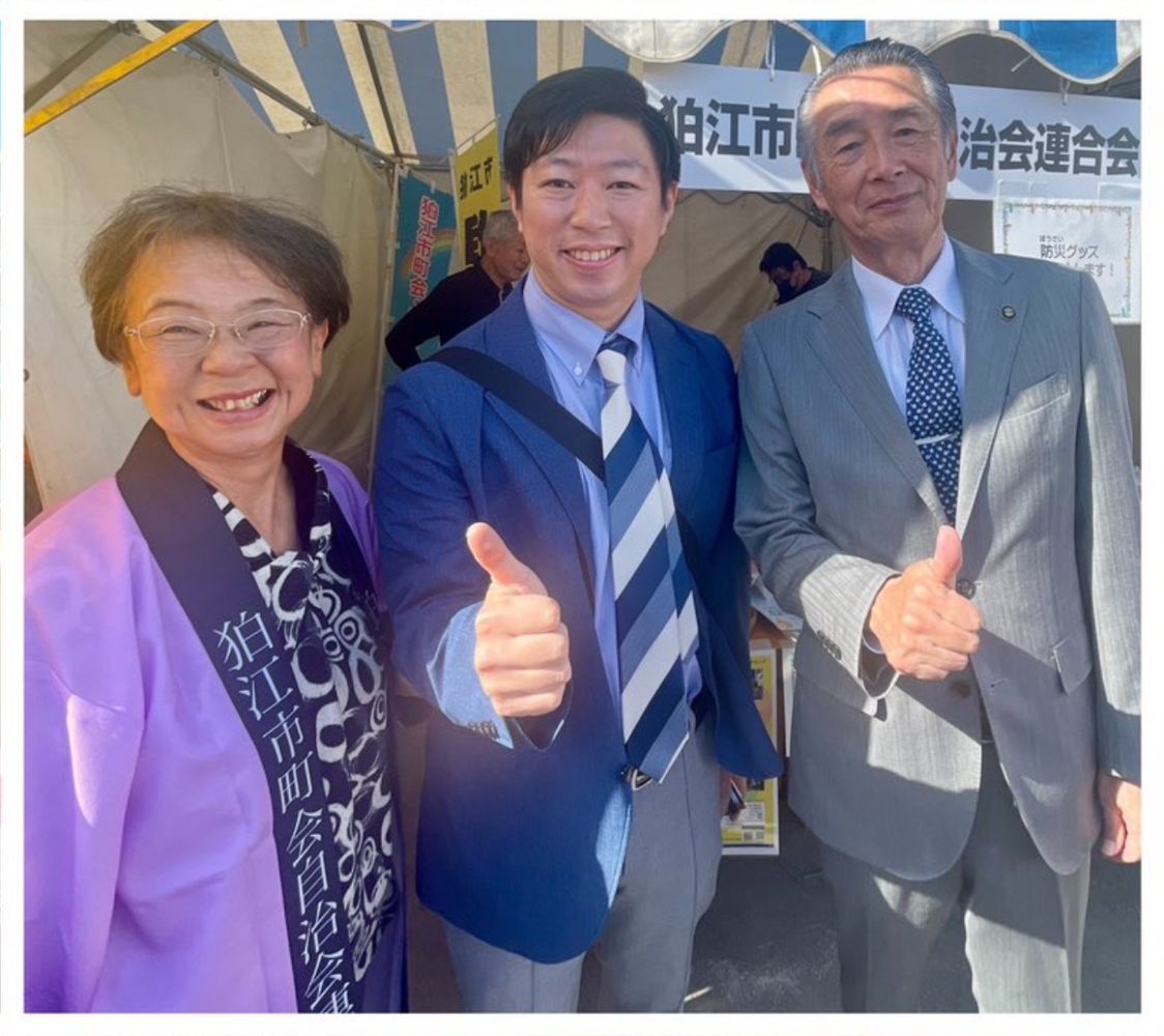 地域の方と笑顔で写るいいだ健一